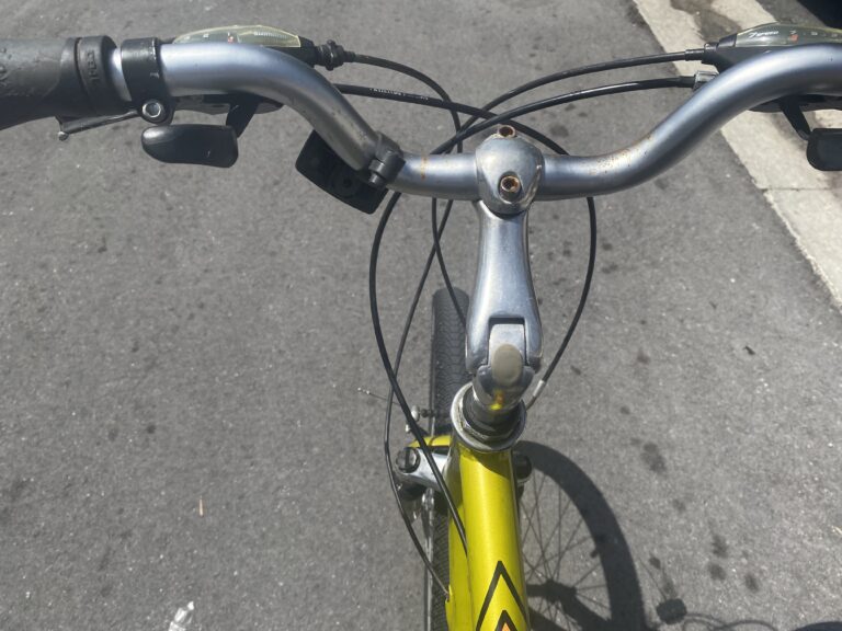 Rusty bike handlebar and front fork on a pavement.