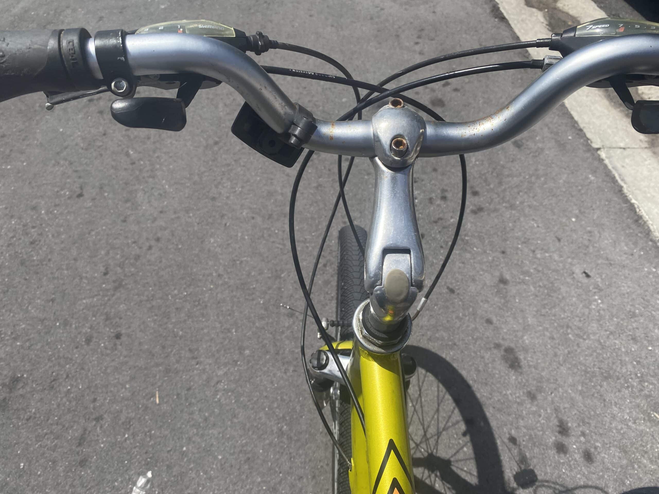 Rusty bike handlebar and front fork on a pavement.