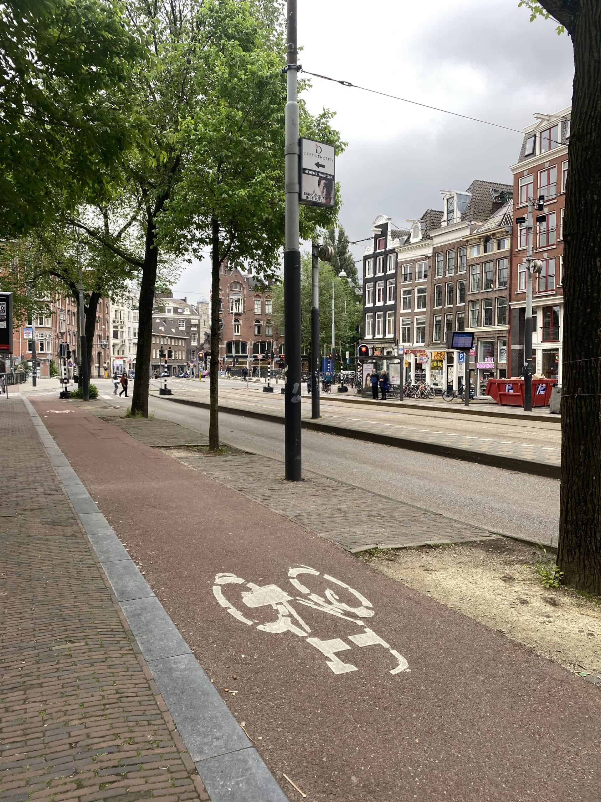 Bike lane on a city street with classic Dutch architecture and tram tracks in the background.