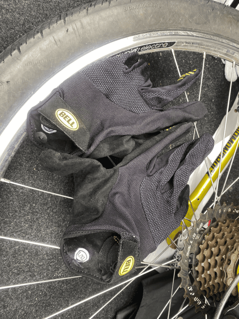 - Padded cycling gloves lying on bike wheel and gear components.